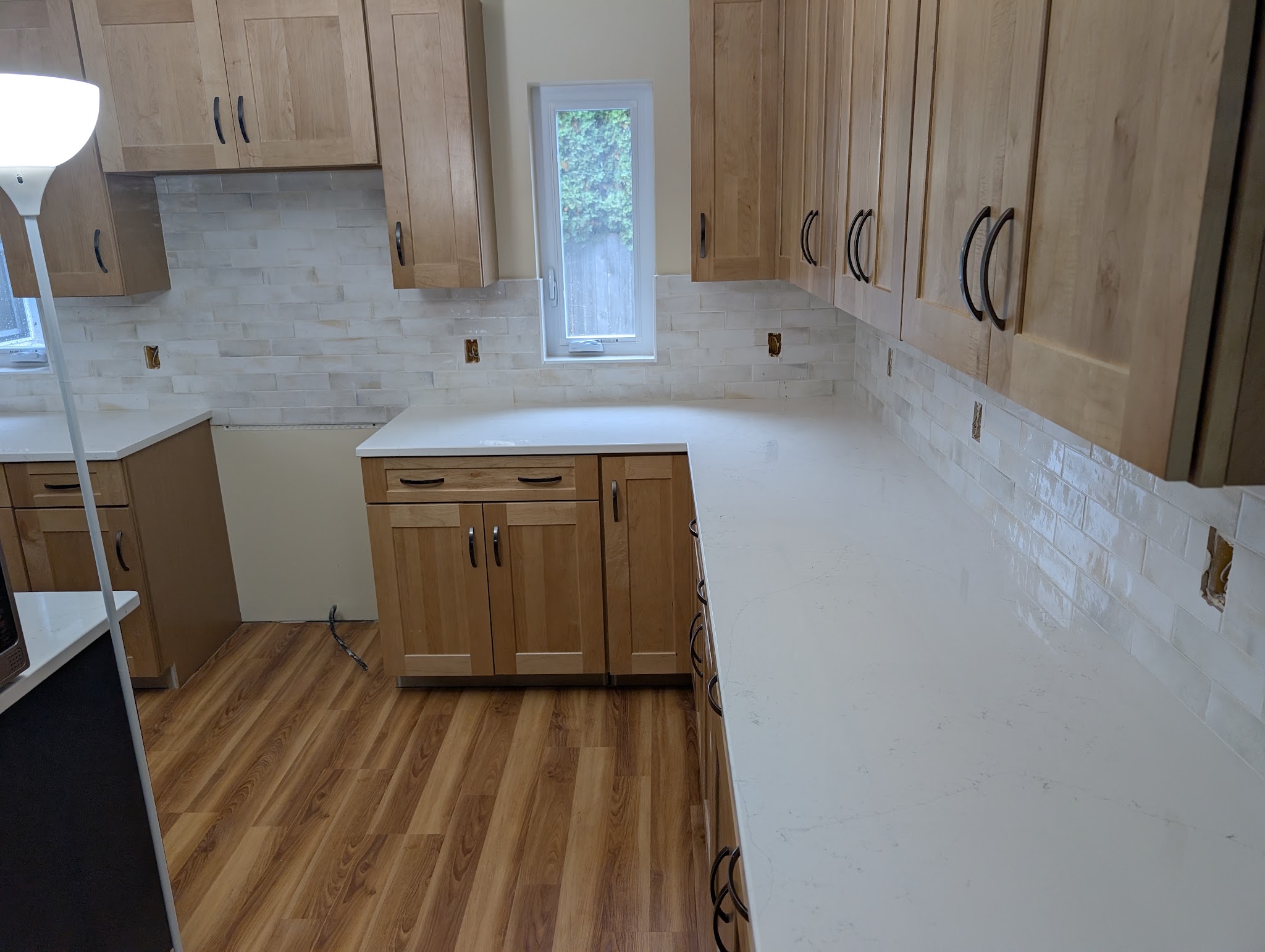 Light kitchen backsplash installed beneath natural wood cabinets