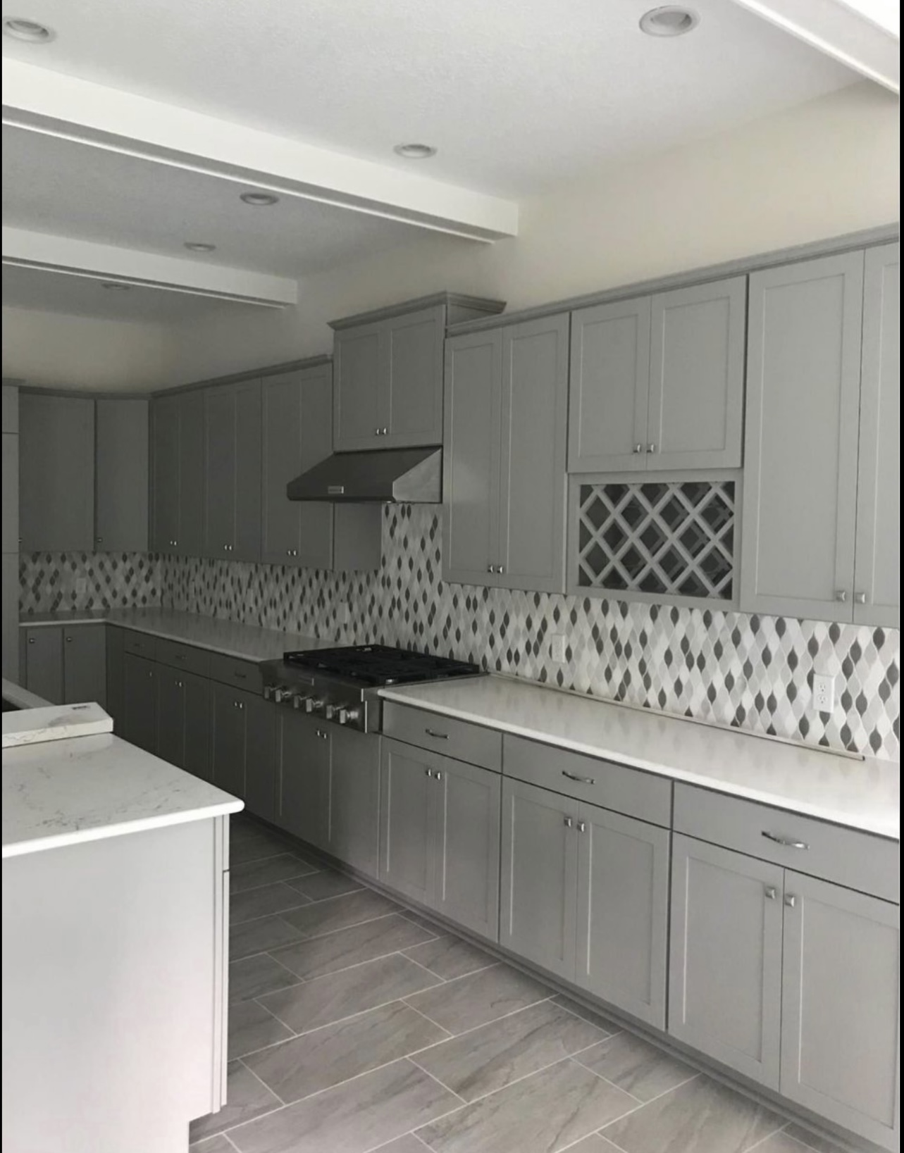 Patterned kitchen backsplash with gray cabinetry and tiled flooring