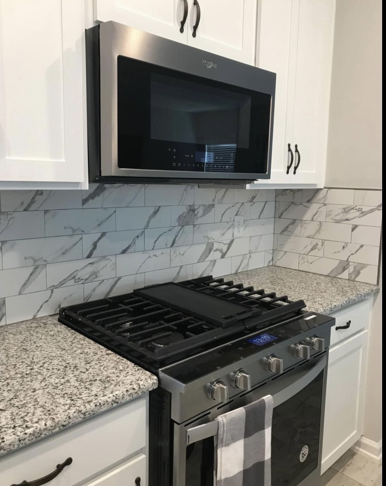 Close view of marble patterned backsplash tile behind a kitchen range